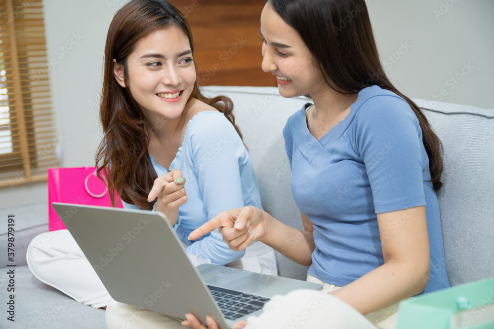 Beautiful young asian women happy couple sitting on sofa buying online using laptop a computer and phone in living room at home. Beautiful young asian women happy couple sitting on sofa buying online using laptop a computer and phone in living room at home.
