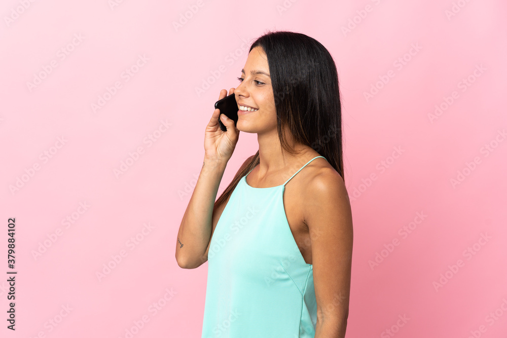 Caucasian girl isolated on pink background keeping a conversation with the mobile phone Caucasian girl isolated on pink background keeping a conversation with the mobile phone