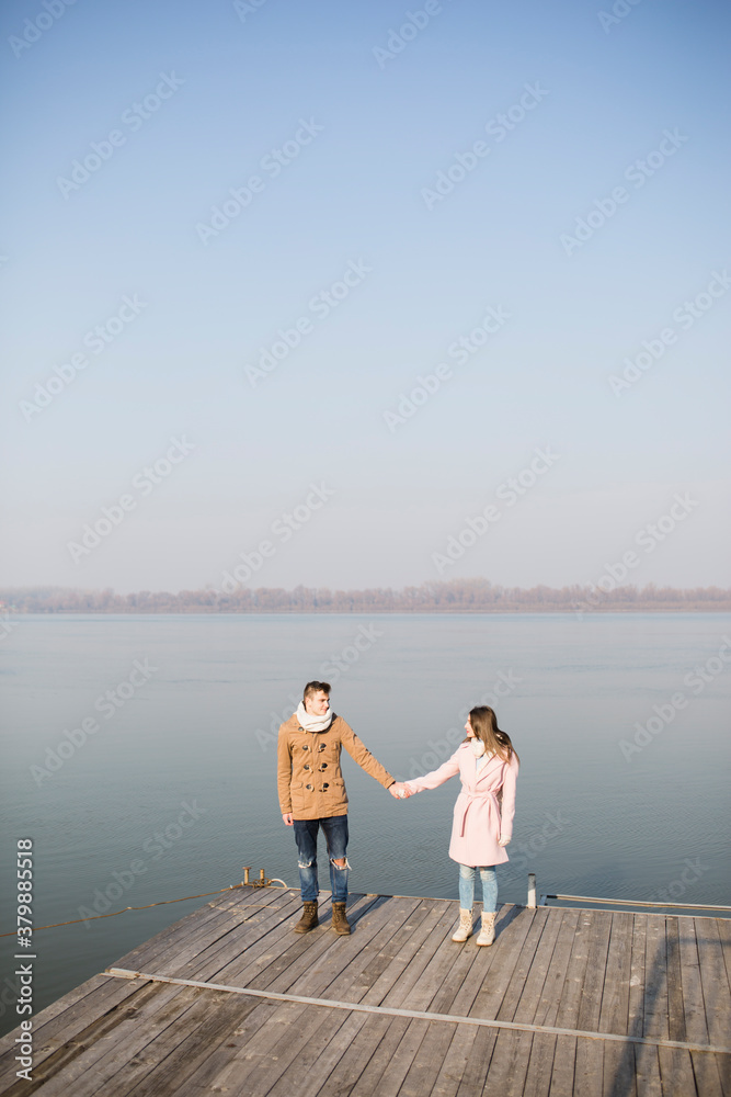 Happy couple in love standing on the dock at the lake Happy couple in love standing on the dock at the lake