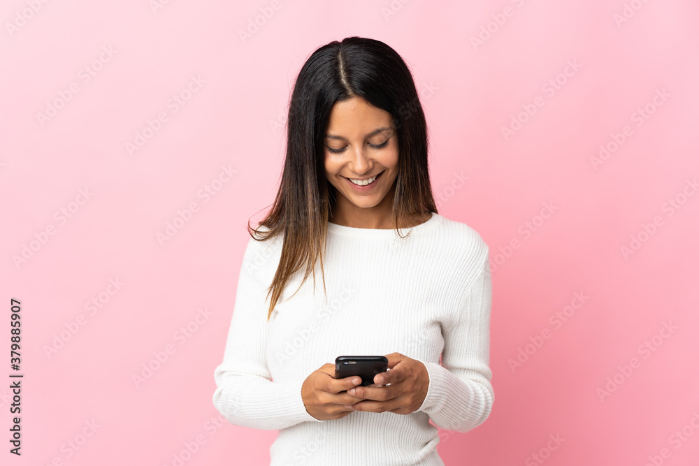 Caucasian girl isolated on pink background sending a message with the mobile Caucasian girl isolated on pink background sending a message with the mobile