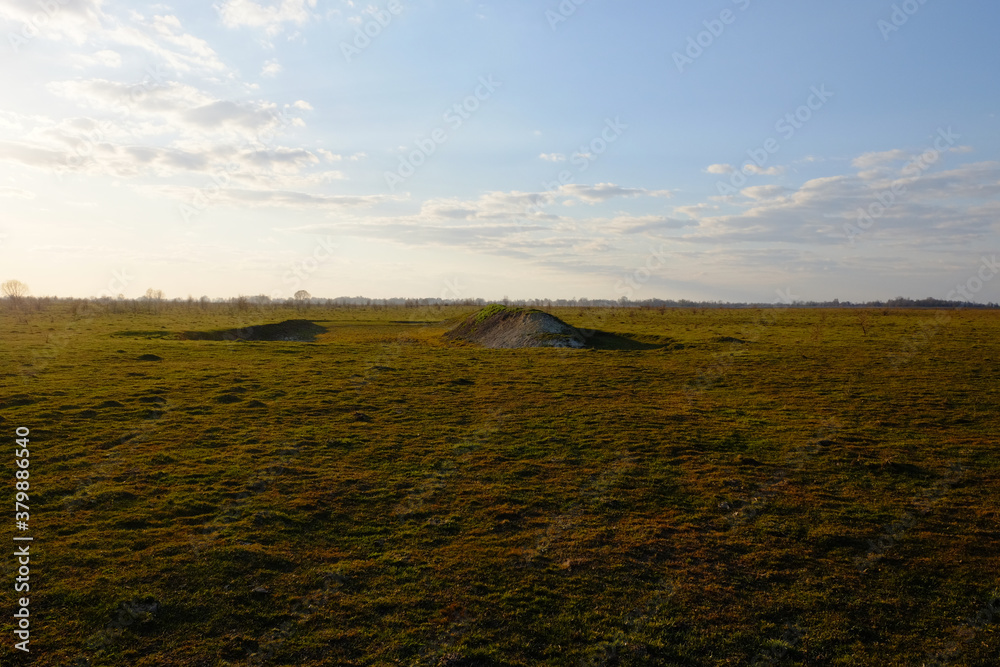 Fototapeta premium Hill in the field. Yellowed grass. Evening sky over the field.