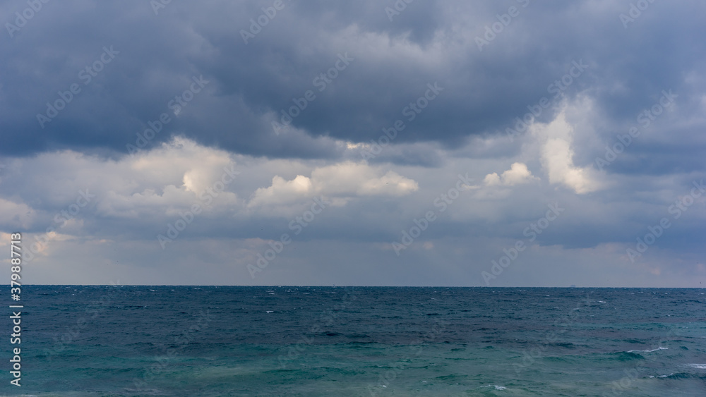 dramatic clouds in the sky over the sea, before the rain, heavy weather, grey clouds, turquoise ocean, soft focus, film noise