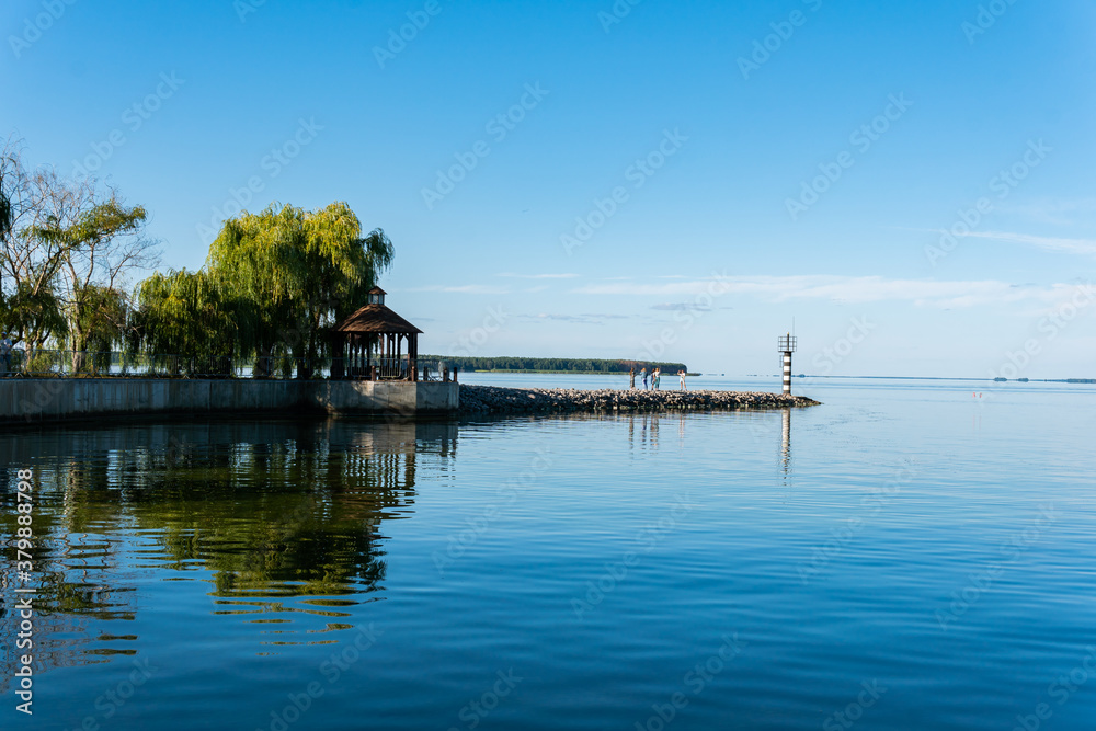 A little lighthouse and see on a sunny summer day, calm blue water and sky, bower, summerhouse, pavilion