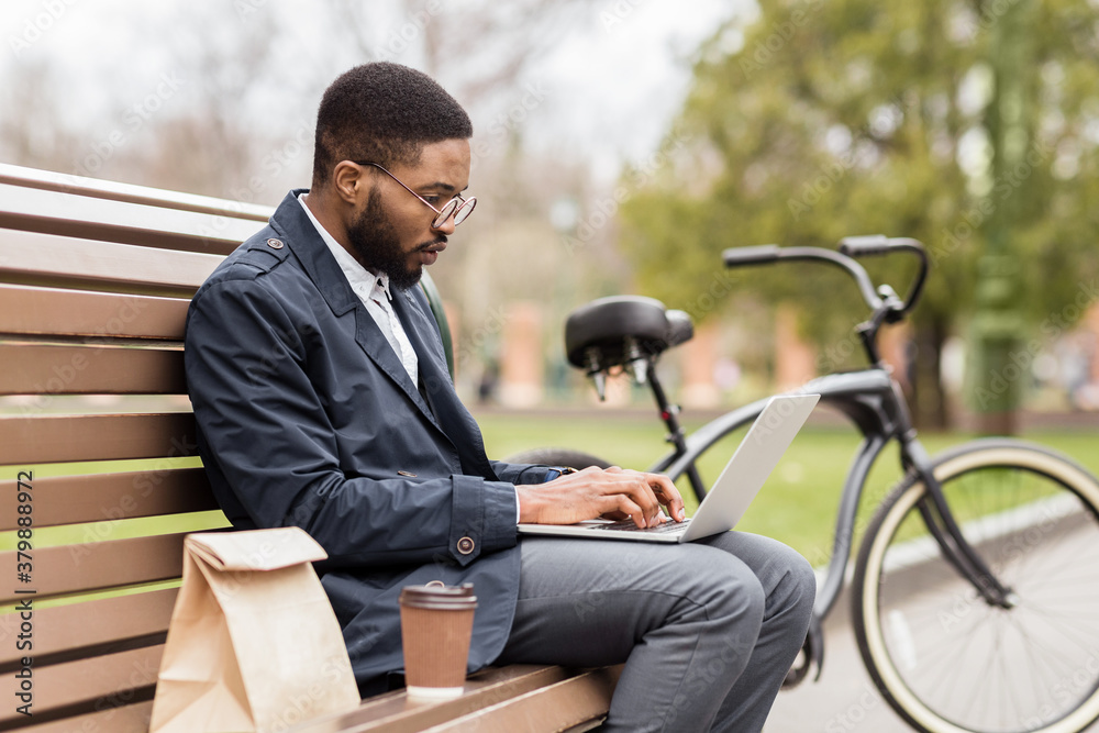 Handsome manager working on laptop in park in spring Handsome manager working on laptop in park in spring
