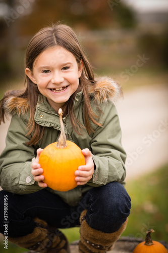 Portrait of Happy Girl Holding a Small Pumpkin During Autumn Outside