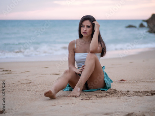Mujer joven posando en la playa durante el atardecer