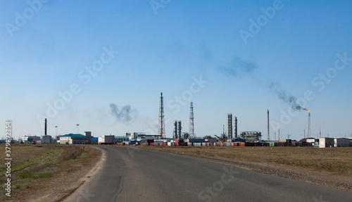 Oil refinery and gas processing plant. View of communication tower  refining columns  gas torch mast  pipelines and industrial building against clear  blue sky.