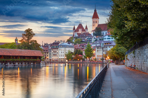 Thun, Switzerland. Cityscape image of beautiful city of Thun with the reflection of the city in the Aare river at sunset. photo