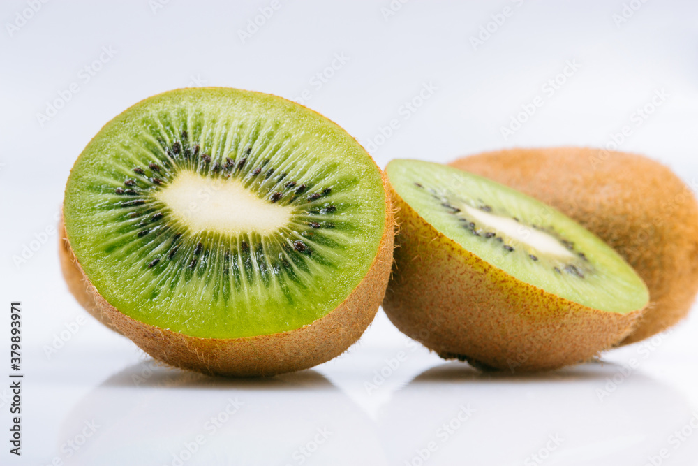 Ripe whole kiwi fruit and half kiwi fruit on bright background.