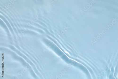 de-focused. Blurred transparent blue colored clear calm water surface texture with splashes and bubbles. Trendy abstract nature background. Water waves in sunlight with copy space.