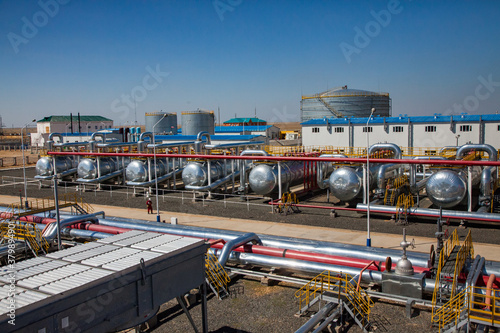 Petrochemical plant. Panorama of oil refinery plant in desert. Heat exchangers, oil storage tanks, pipelines and factory building.