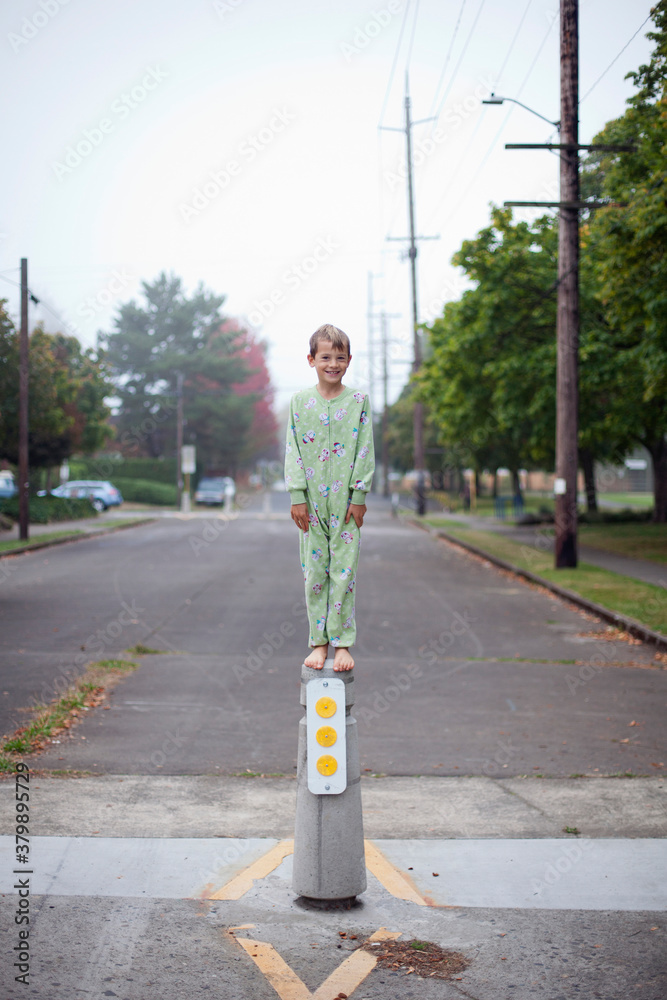 Barefoot boy in pajamas stands on top of concrete pylon Barefoot boy in pajamas stands on top of concrete pylon