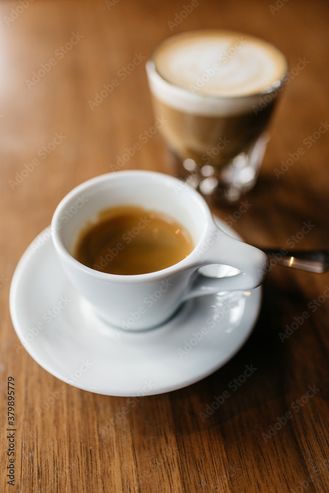 Two coffees sitting on a table, an espresso and a macchiato Two coffees sitting on a table, an espresso and a macchiato
