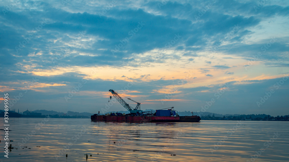 A ship with crane on Mahakam River, Samarinda in the morning. 