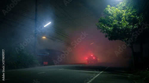 Pickup truck drive into fog on road with in silent town photo