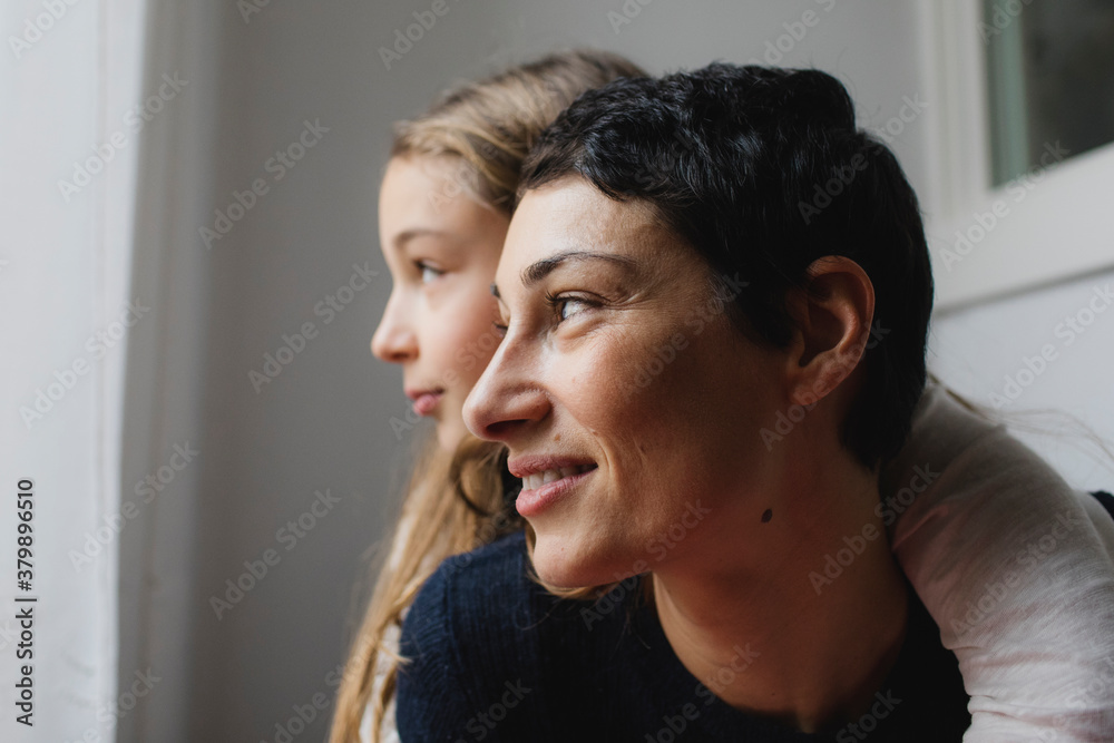Little girl and her mom look out the window