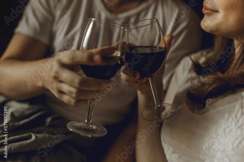 Man and woman clanging wine glasses of wine at the bad 