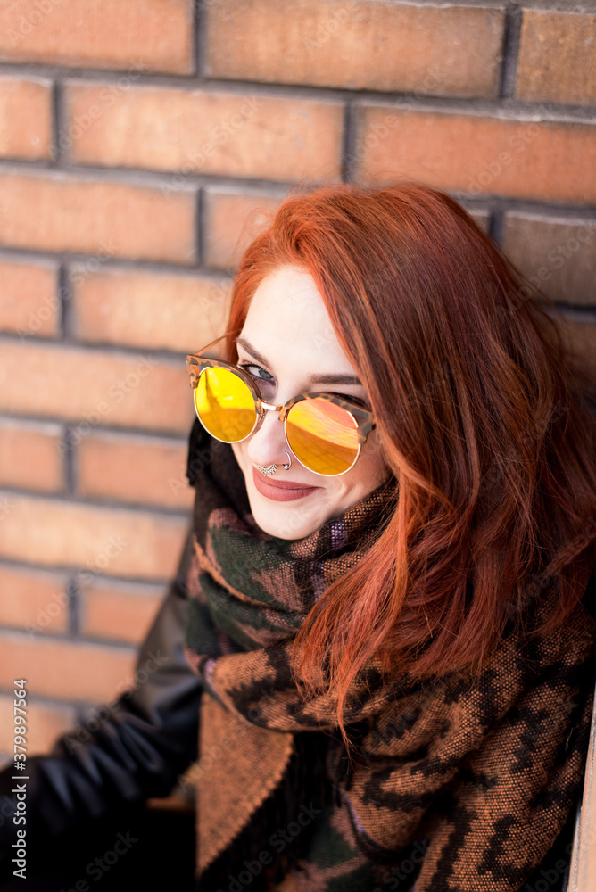 Portrait of beautiful ginger woman with sunglasses in front of bricks Portrait of beautiful ginger woman with sunglasses in front of bricks
