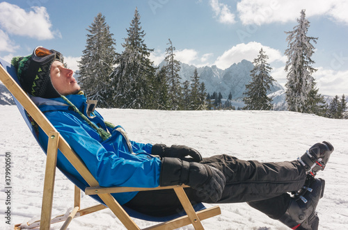 Man resting on chaise longue outdoor on the ski slope photo