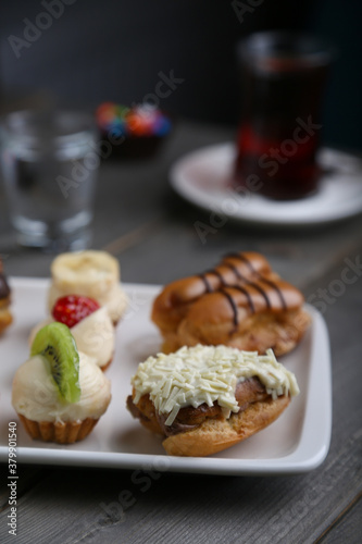 Eclairs and mini tarts on a white plate and tea