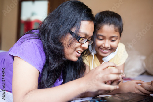 Sisters making fun with Laptop and smartphone photo