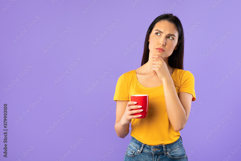Pensive woman holding coffee mug at studio Pensive woman holding coffee mug at studio