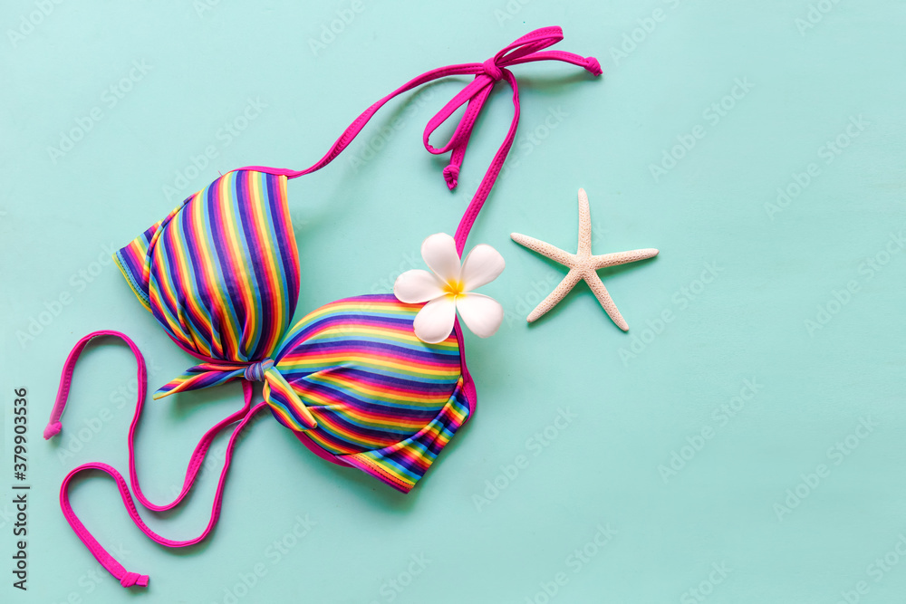 Fototapeta premium Summer items and accessories traveler woman colorful bikini with flower frangipani to travel plan holiday vacation in the beach. Tropical sea.