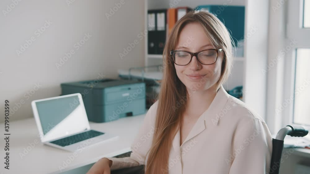 Portrait of young disabled woman in the office smiling towards camera. High quality 4k footage