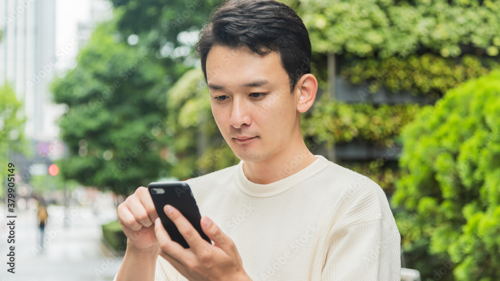 オフィス街でスマートフォンを操作する若い男性