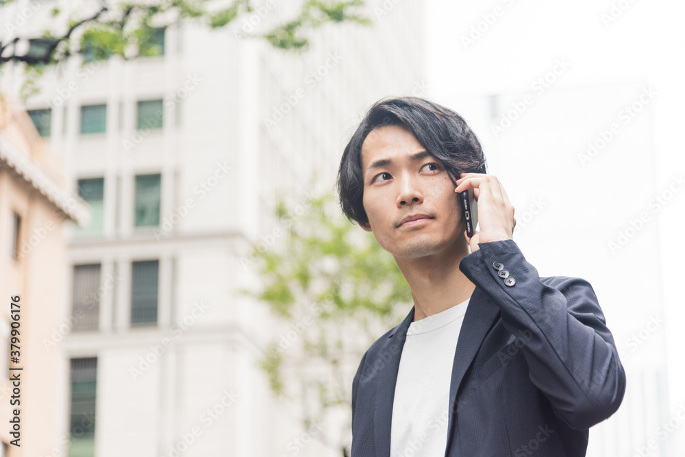 オフィス街で電話をする若い男性 オフィス街で電話をする若い男性