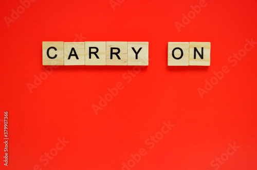 Word carry on. Wooden blocks with lettering on top of red background. Top view of wooden blocks with letters on red surface