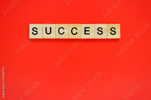 Word success. Wooden blocks with lettering on top of red background. Top view of wooden blocks with letters on red surface