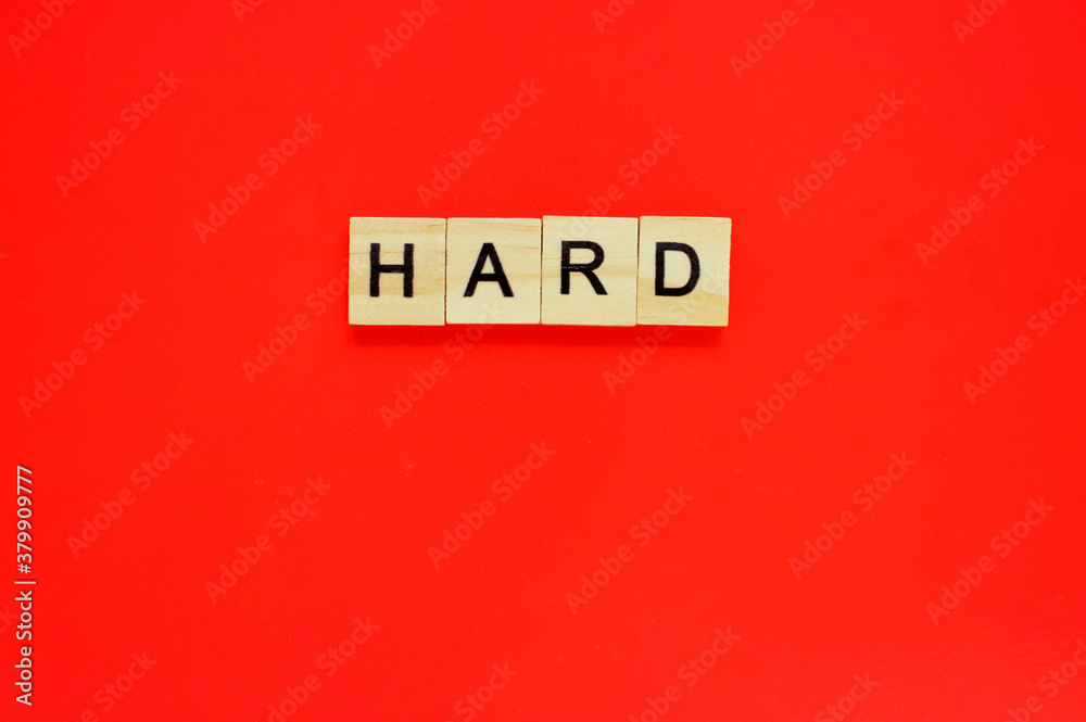 Word hard. Wooden blocks with lettering on top of red background. Top view of wooden blocks with letters on red surface Word hard. Wooden blocks with lettering on top of red background. Top view of wooden blocks with letters on red surface