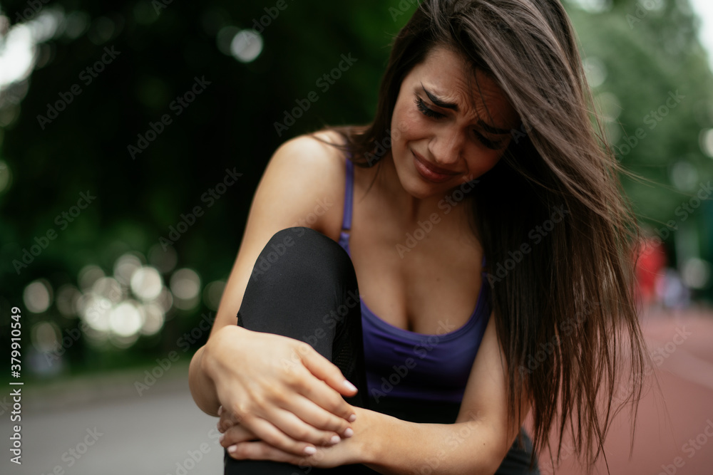 Naklejka premium Sport knee injury. Woman has pain in knee after run outdoors.