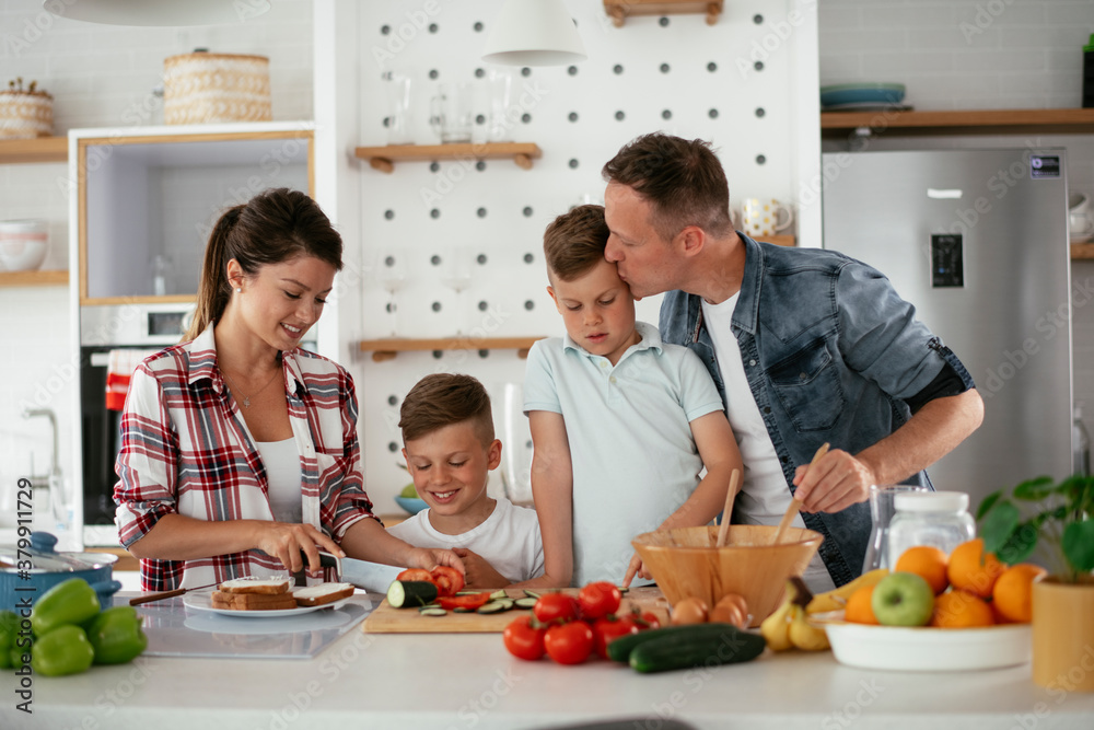 Mother and father making breakfast with sons. Young family preparing delicious food in kitchen.. Mother and father making breakfast with sons. Young family preparing delicious food in kitchen..