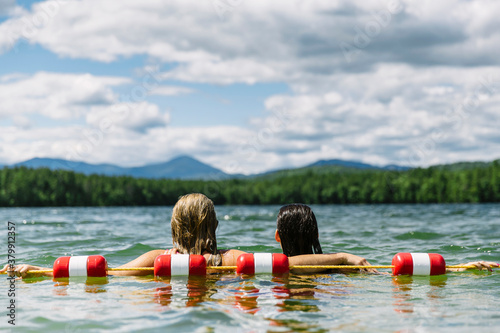 Two Friends Arm in Arm Swimming at Lake photo