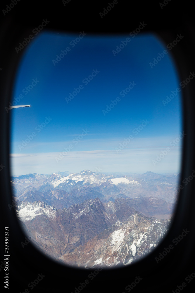 View of the mountains trough the airplane window high above the ground View of the mountains trough the airplane window high above the ground