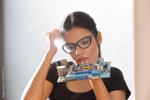 Executive looking at motherboard with a torch in her hand	 photo