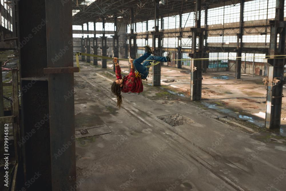 Man hanging on highline in abandoned industrial area Man hanging on highline in abandoned industrial area