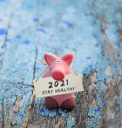Photography Kleines rosa Glücksschwein, mit Tafel und Aufschrift: 2021 Stay Healthy, auf altem, blauen Holz