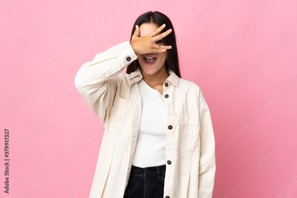 Teenager girl isolated on pink background covering eyes by hands and smiling