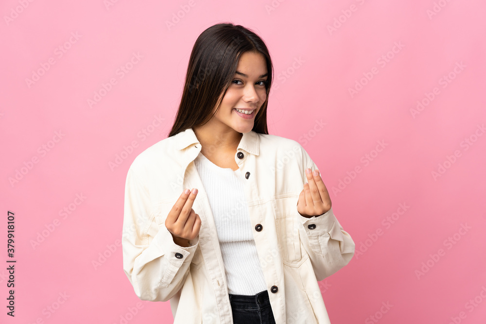 Teenager girl isolated on pink background making money gesture