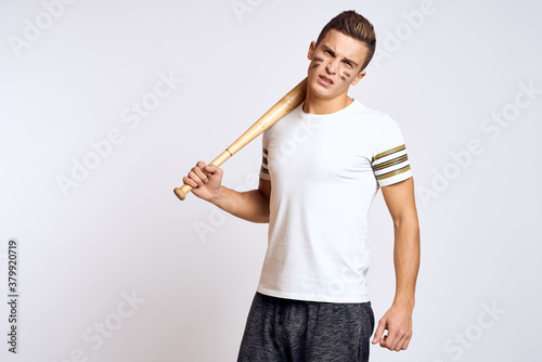 a man with a baseball bat on a light background exercises kicks sport ball model