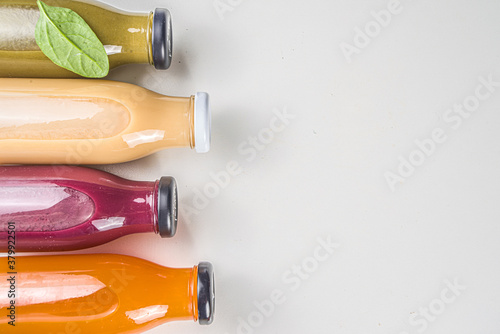 Fruit and vegetable smoothie concept. Portioned bottles with fruit and vegetable smoothies flatlay with fresh ingredients on white table background