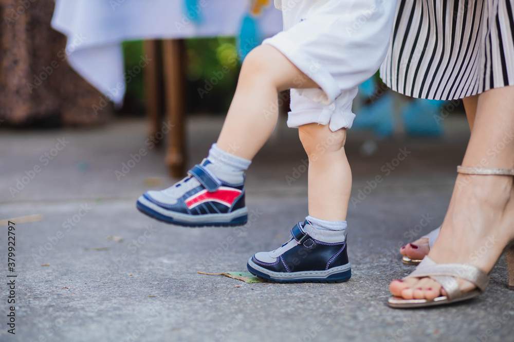 Mom helping her baby son to walk. Parenting concept