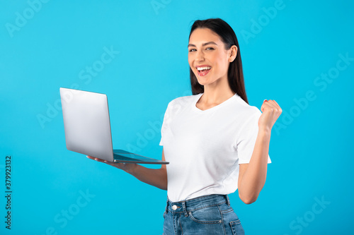 Schilderij op canvas Happy female model celebrating win holding laptop