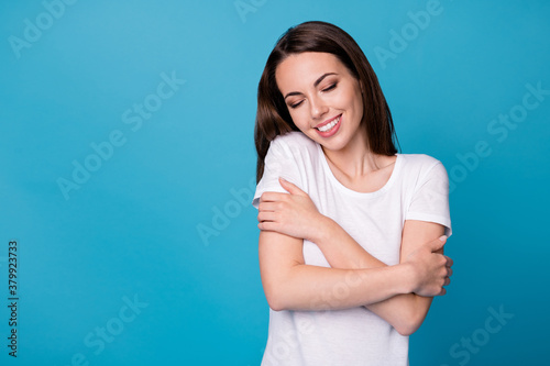 Photo of positive cheerful girl hug herself enjoy cuddle wear casual style outfit isolated over blue color background © deagreez