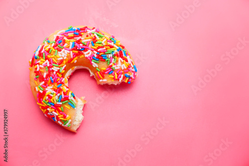 Close up of half eaten donut on pink background 