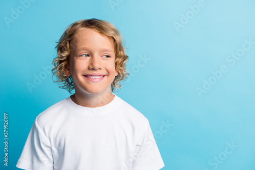 Photo of pretty boy look empty space beaming smiling wear white t-shirt isolated over blue color background