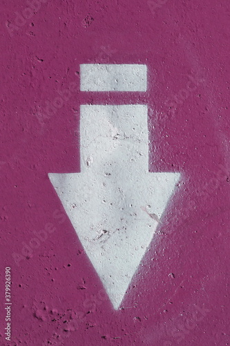 a white print of an arrow directed to down on a purple wall